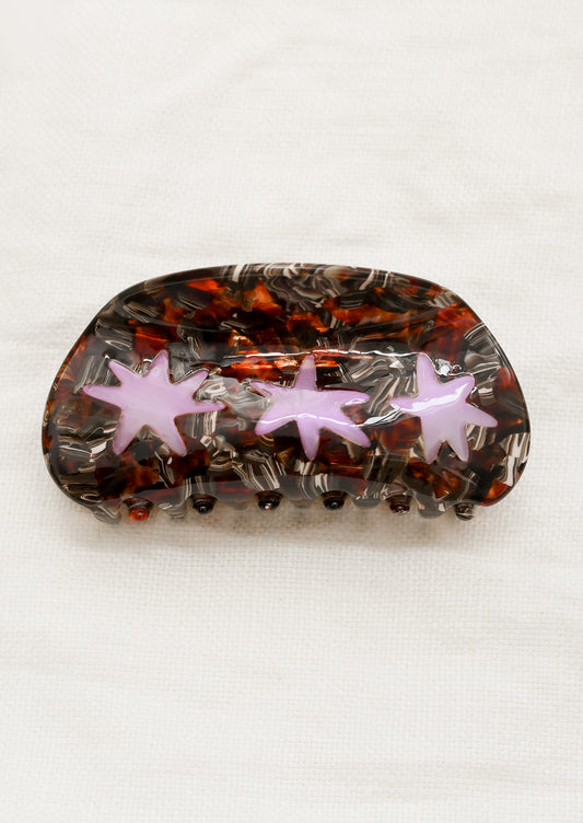A hair claw in brown tortoise with translucent purple starburst design.