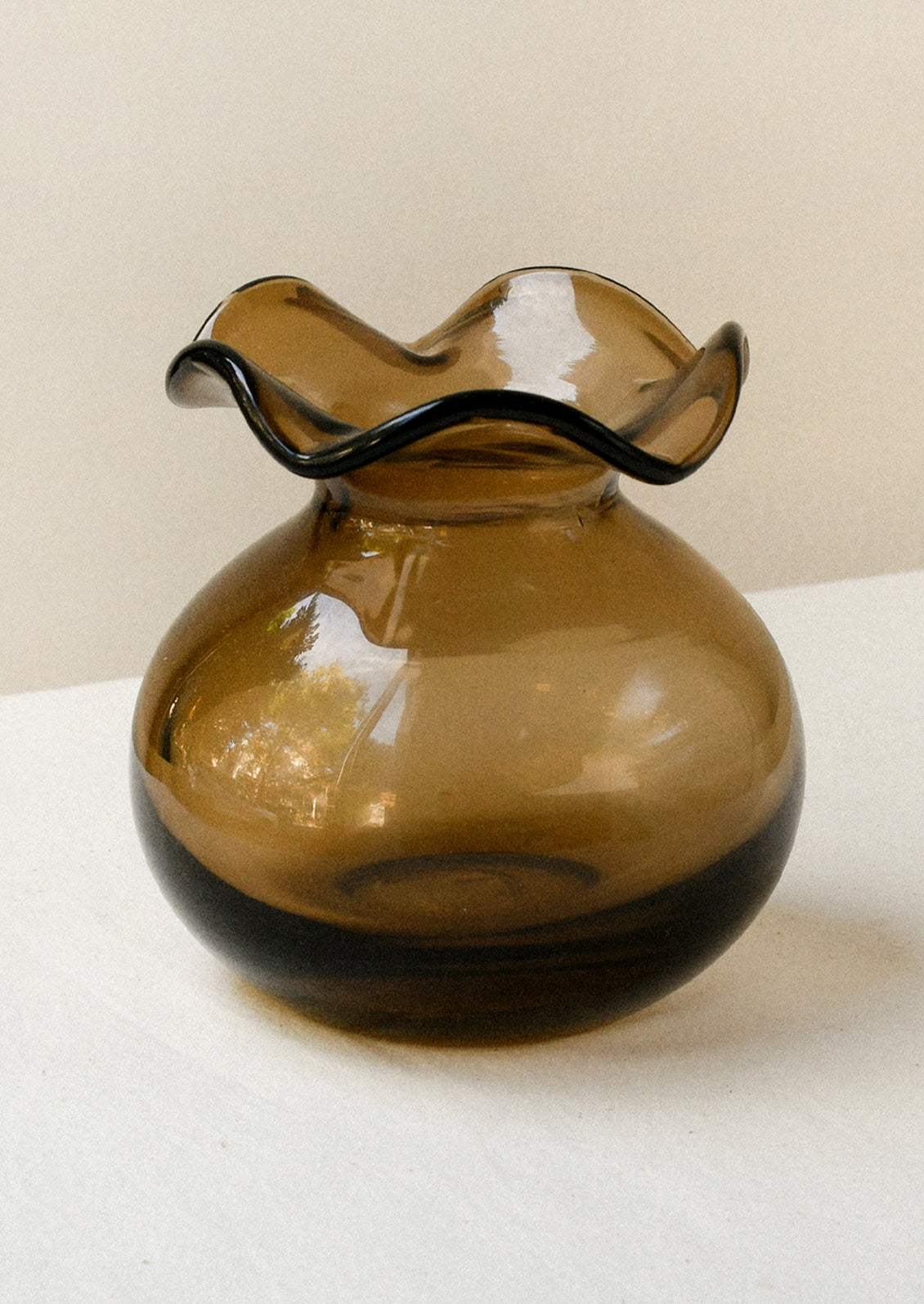 A glass bud vase in chocolate brown with ruffled opening.