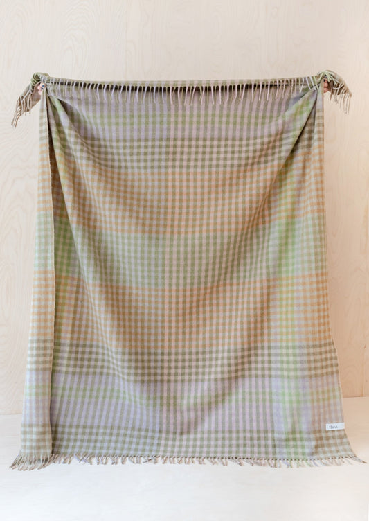 A gingham check print throw in mix of pastel and earthy greens and browns.