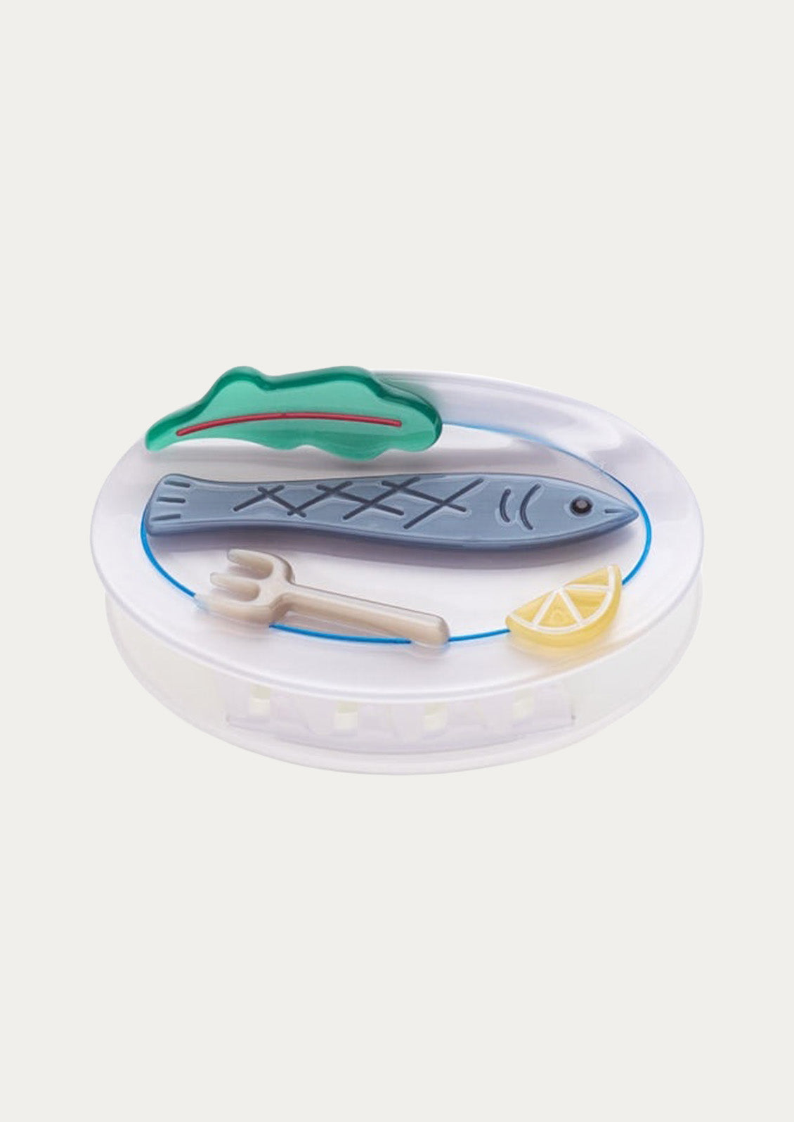 A white claw clip with a sardine, lettuce leaf, fork, and lemon slice on top on a white background.
