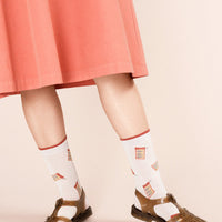 2: A pair of blush colored socks with tinned sardine pattern.