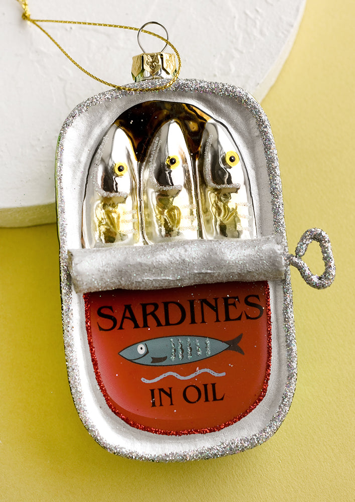 A glass holiday ornament in the style of sardine can.