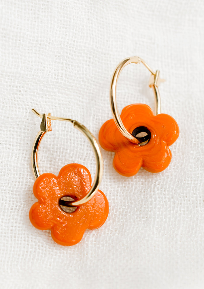A pair of gold hoop earrings with single orange flower bead.