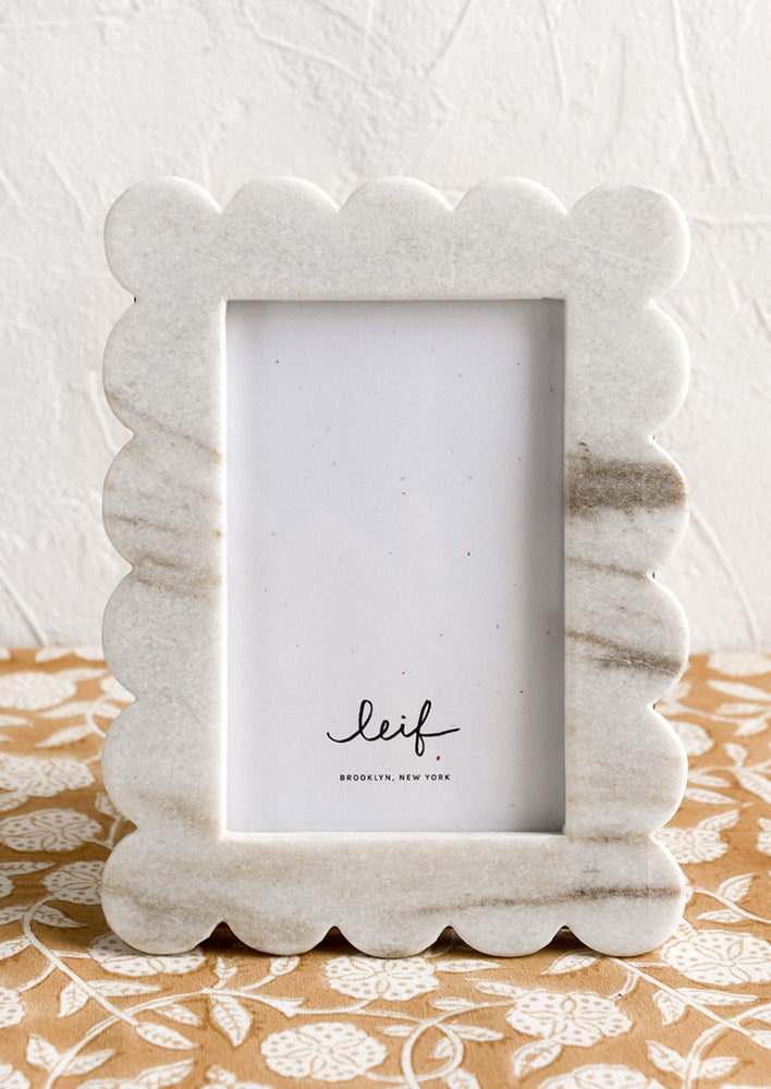 A scalloped marble picture frame in solid grey marble.