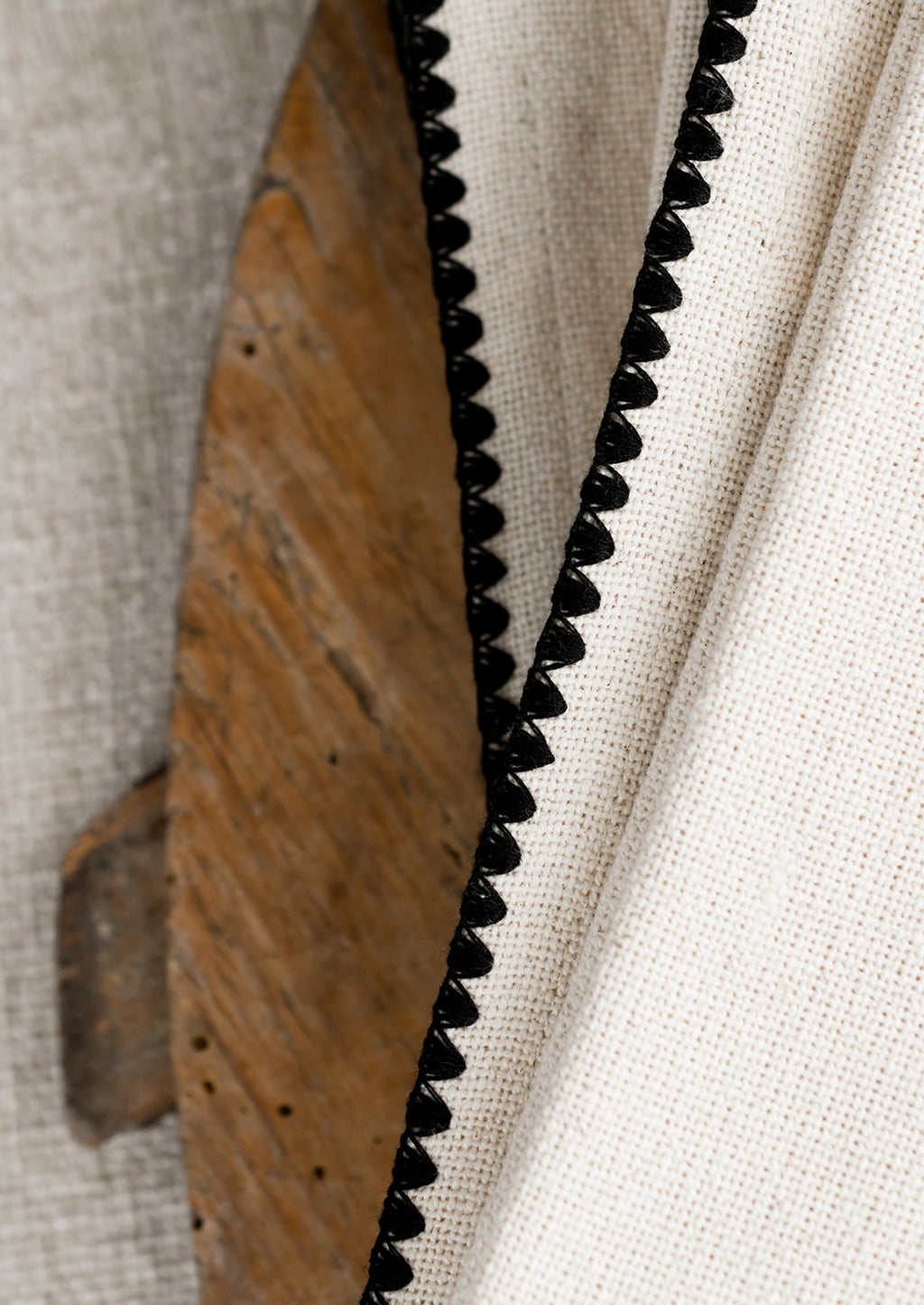3: A stack of natural cotton dinner napkins with scalloped black stitching.