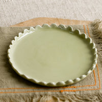 Meadow Green: A round ceramic plate in green with scalloped edges.