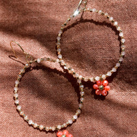 Peach Multi: A pair of beaded hoop earrings with flower charm in peach.