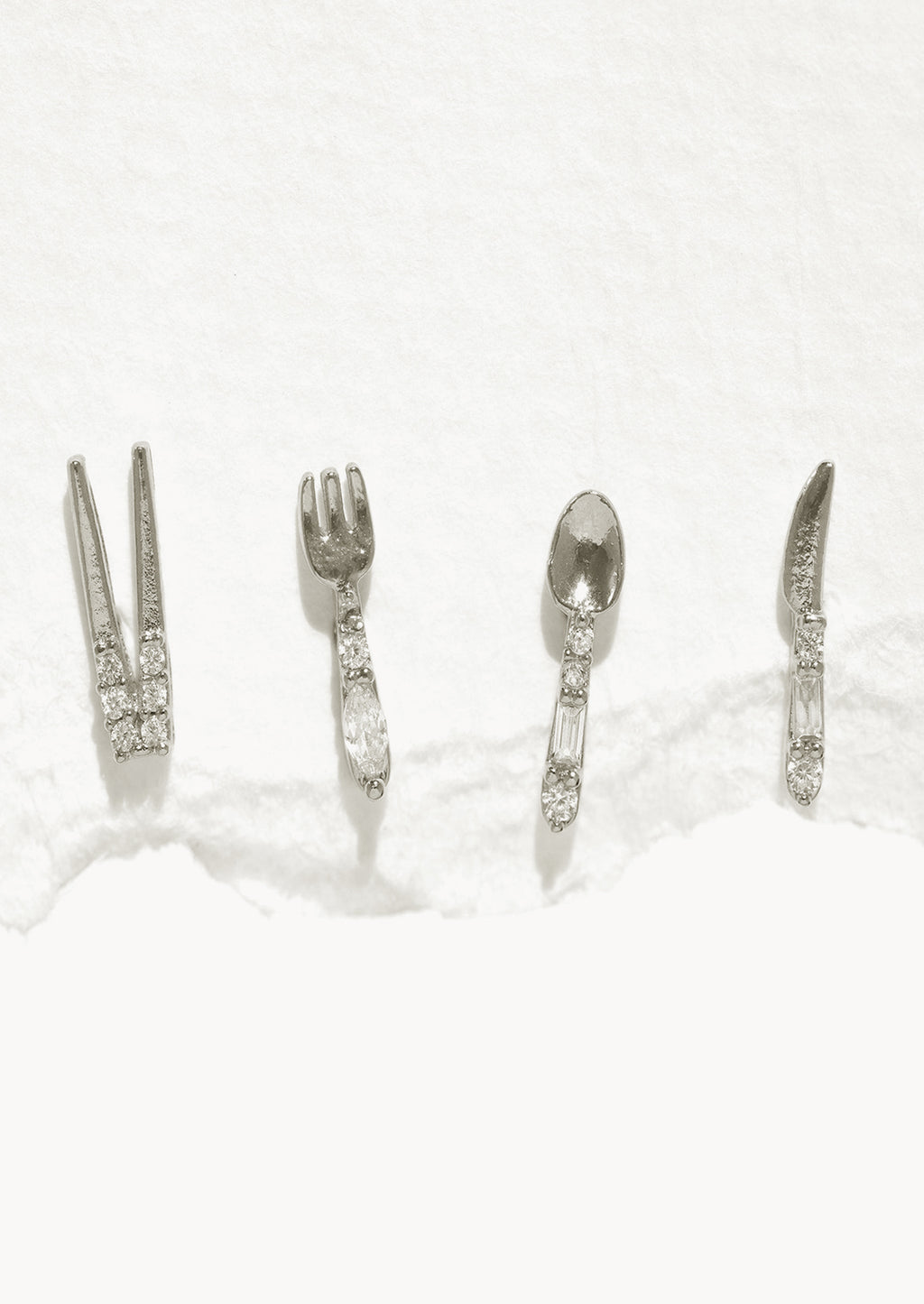 Silver: A set of four silver stud earrings in shape of chopsticks, fork, spoon, and knife.
