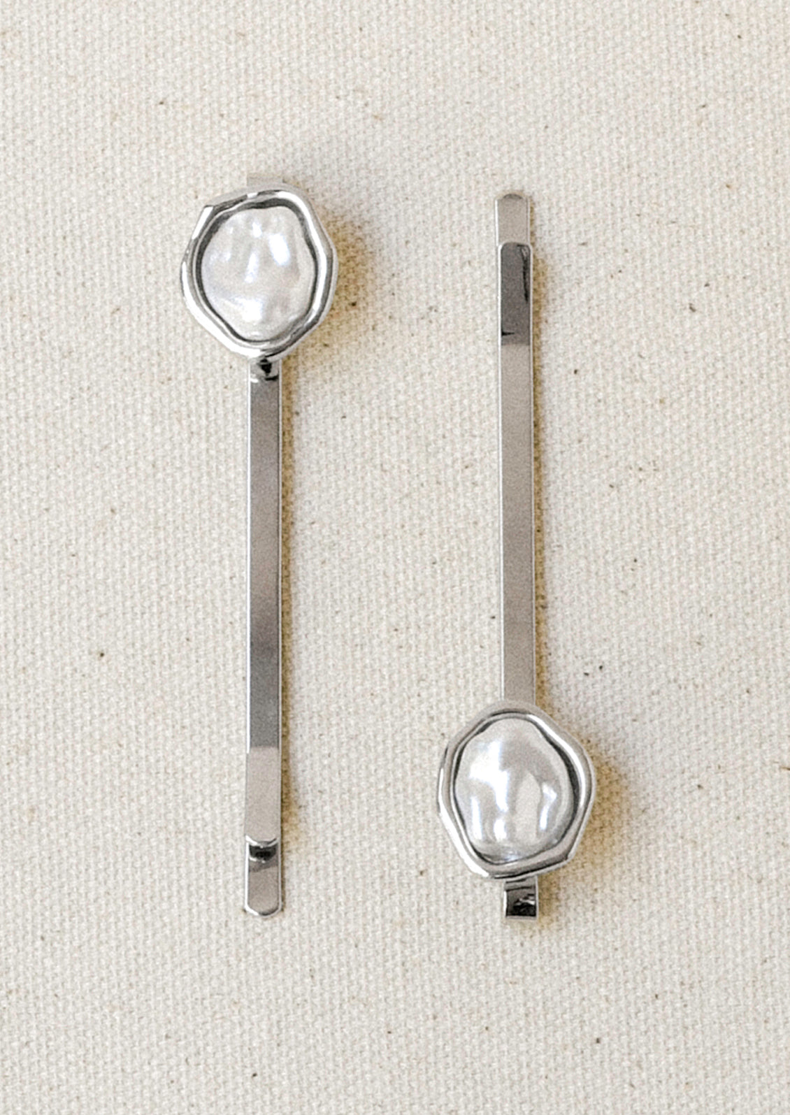 A set of 2 silver hair pins with a faux freshwater pearl on the end of each.