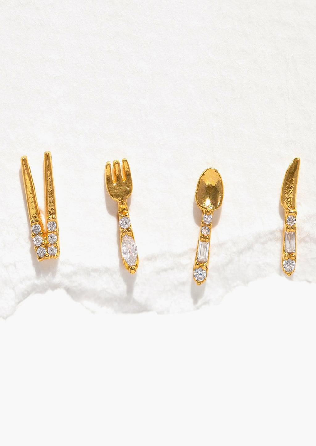 Gold: A set of four gold stud earrings in shape of chopsticks, fork, spoon, and knife.