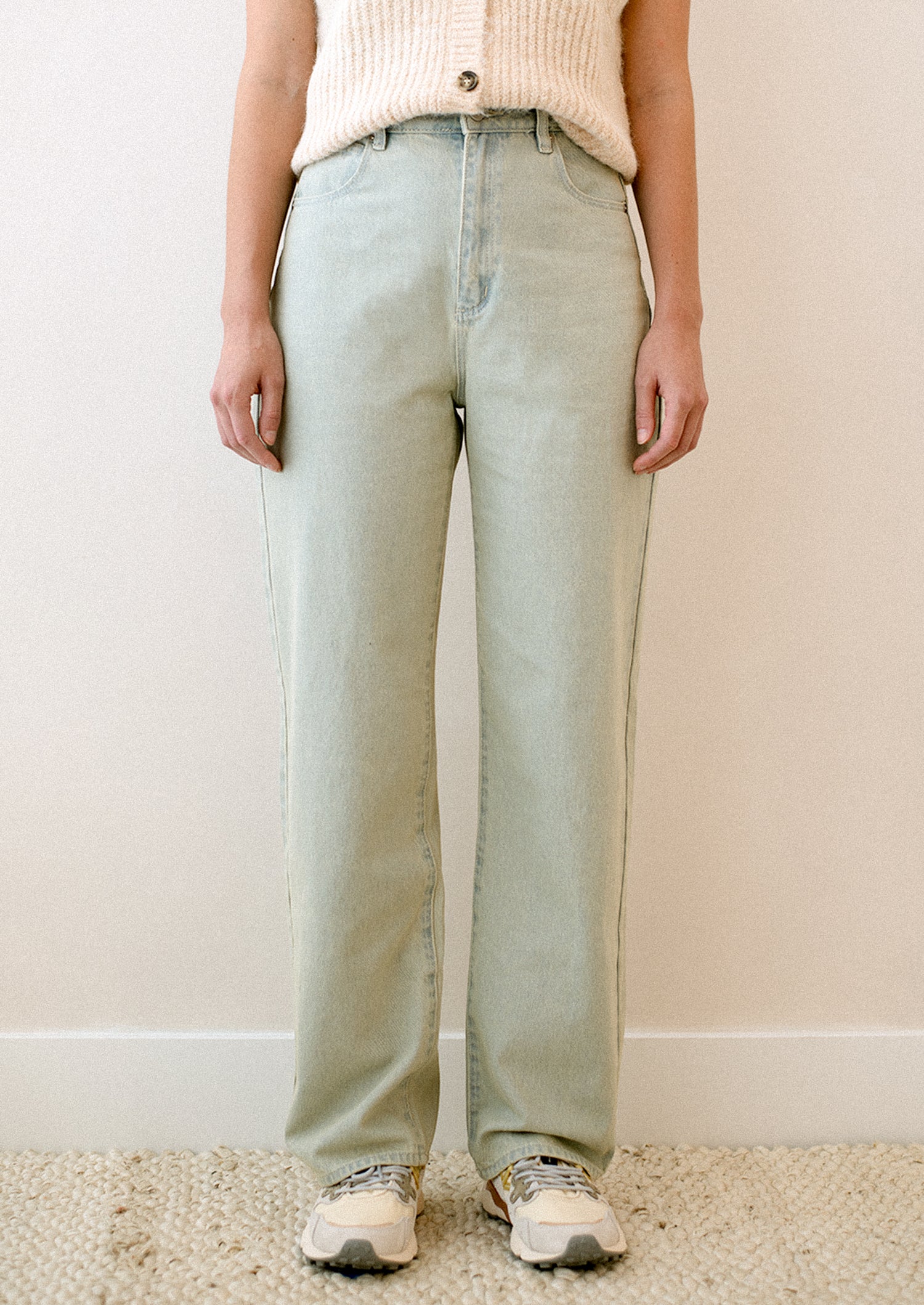 A woman wearing a pair of jeans in subtle green tinted light blue wash.