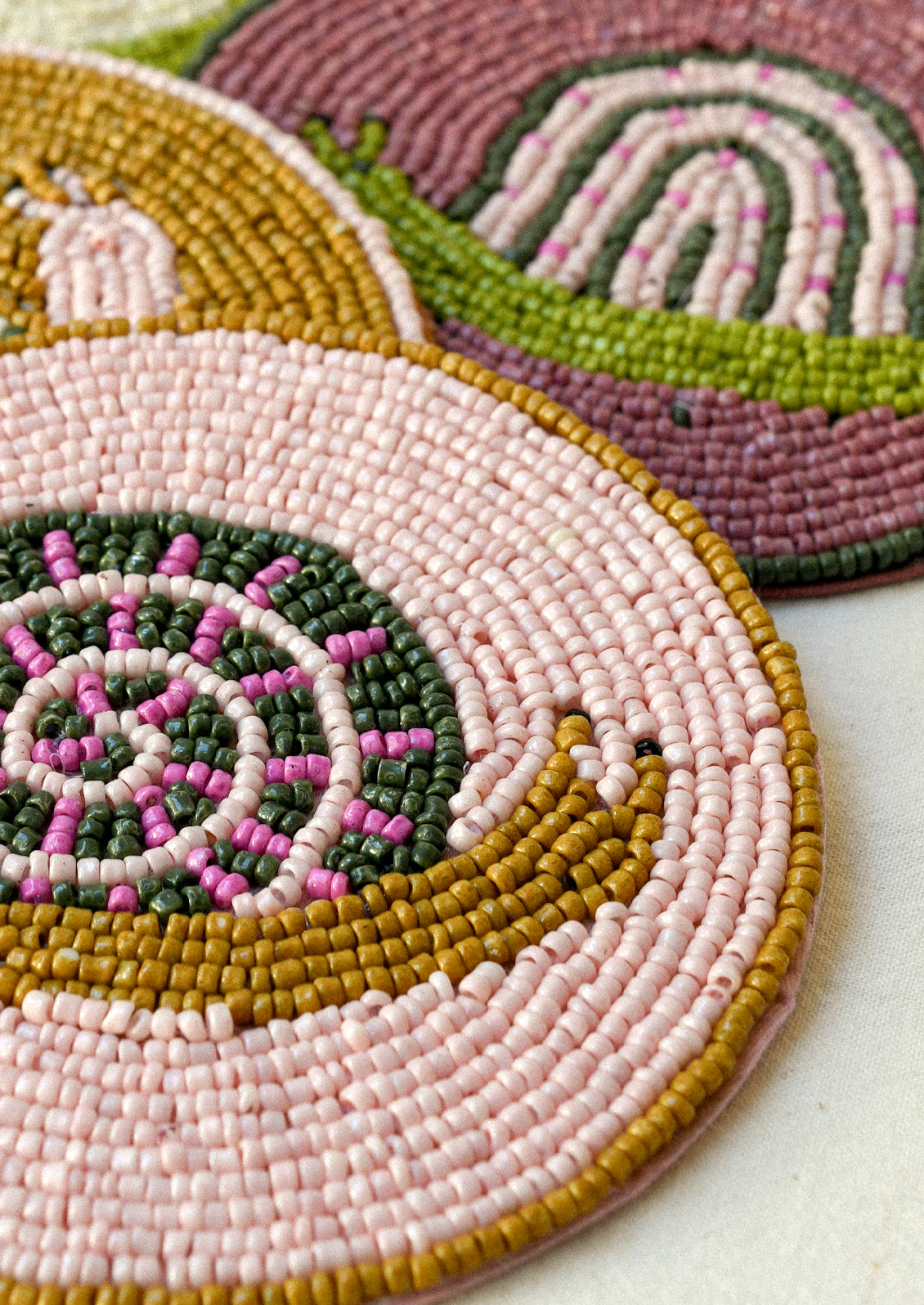 Closeup of a beaded coaster with a snail design.