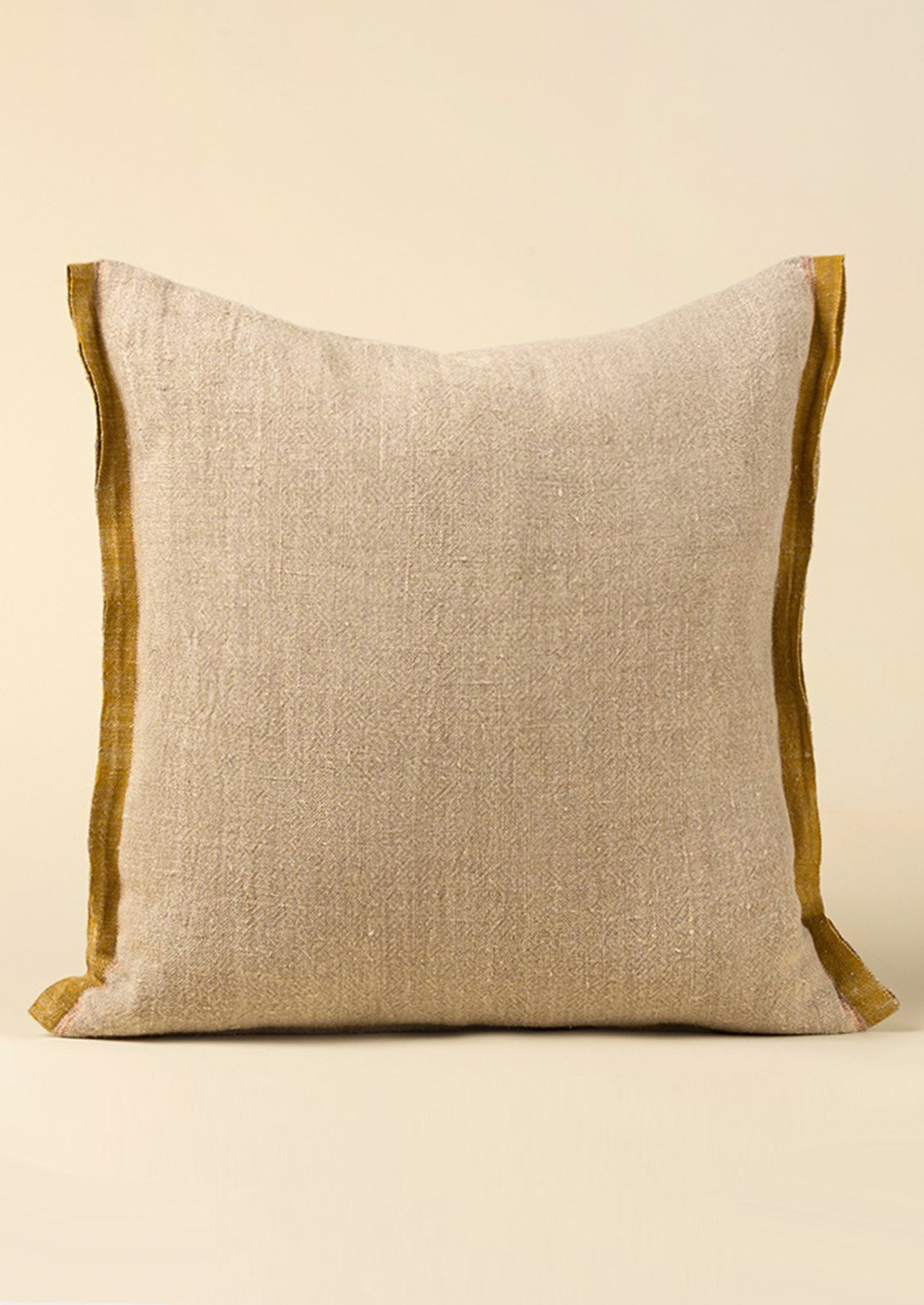 A natural linen throw pillow with mustard decorative selvage trim.