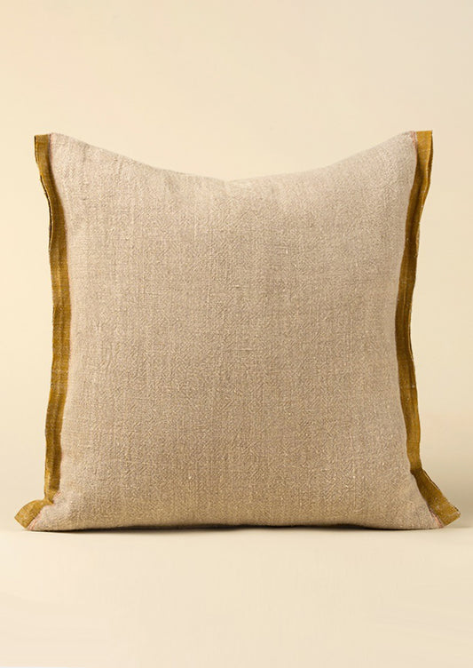 A natural linen throw pillow with mustard decorative selvage trim.