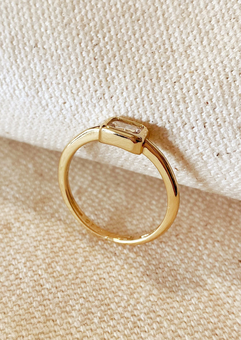 1: A gold ring with single rectangular clear stone.