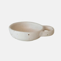 2: A small ceramic pinch bowl in speckled white ceramic with decorative handle.