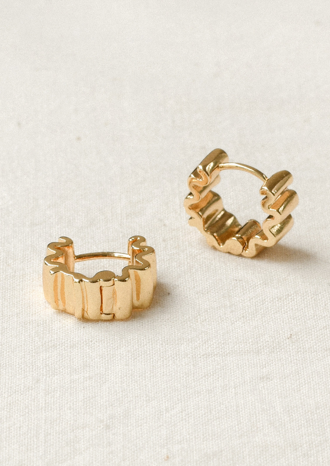 A pair of thick hoop earrings with a squiggle shape design.