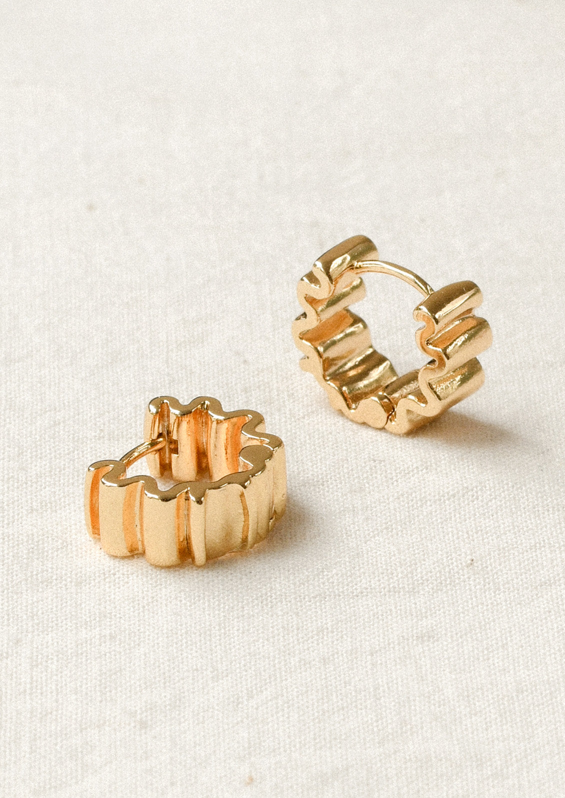 A pair of thick hoop earrings with a squiggle shape design.