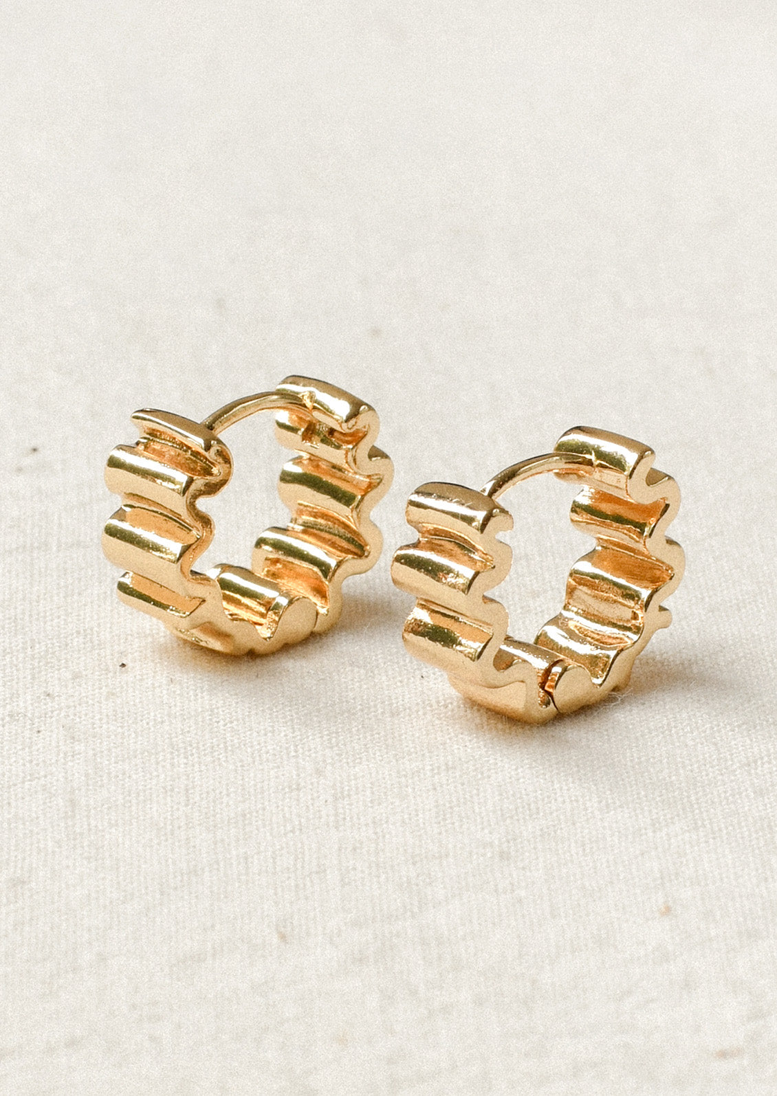 A pair of thick hoop earrings with a squiggle shape design.