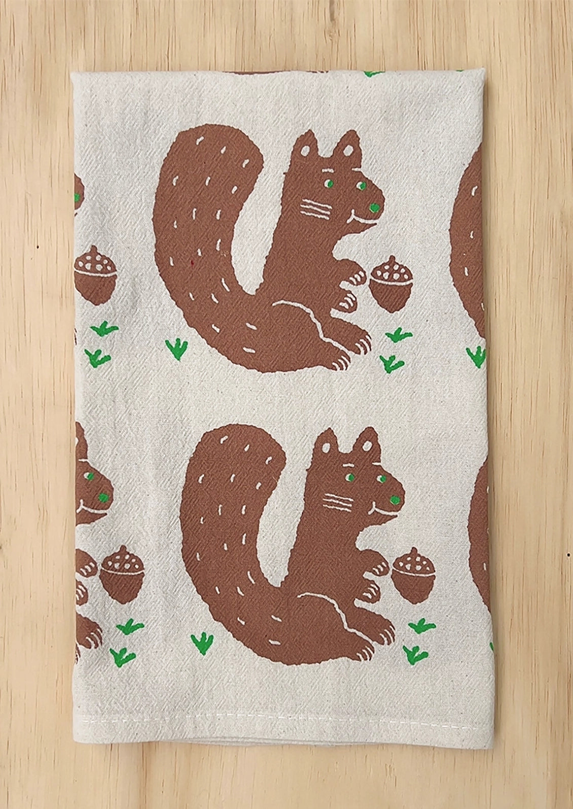 A folded tea towel with repeating squirrel motif.