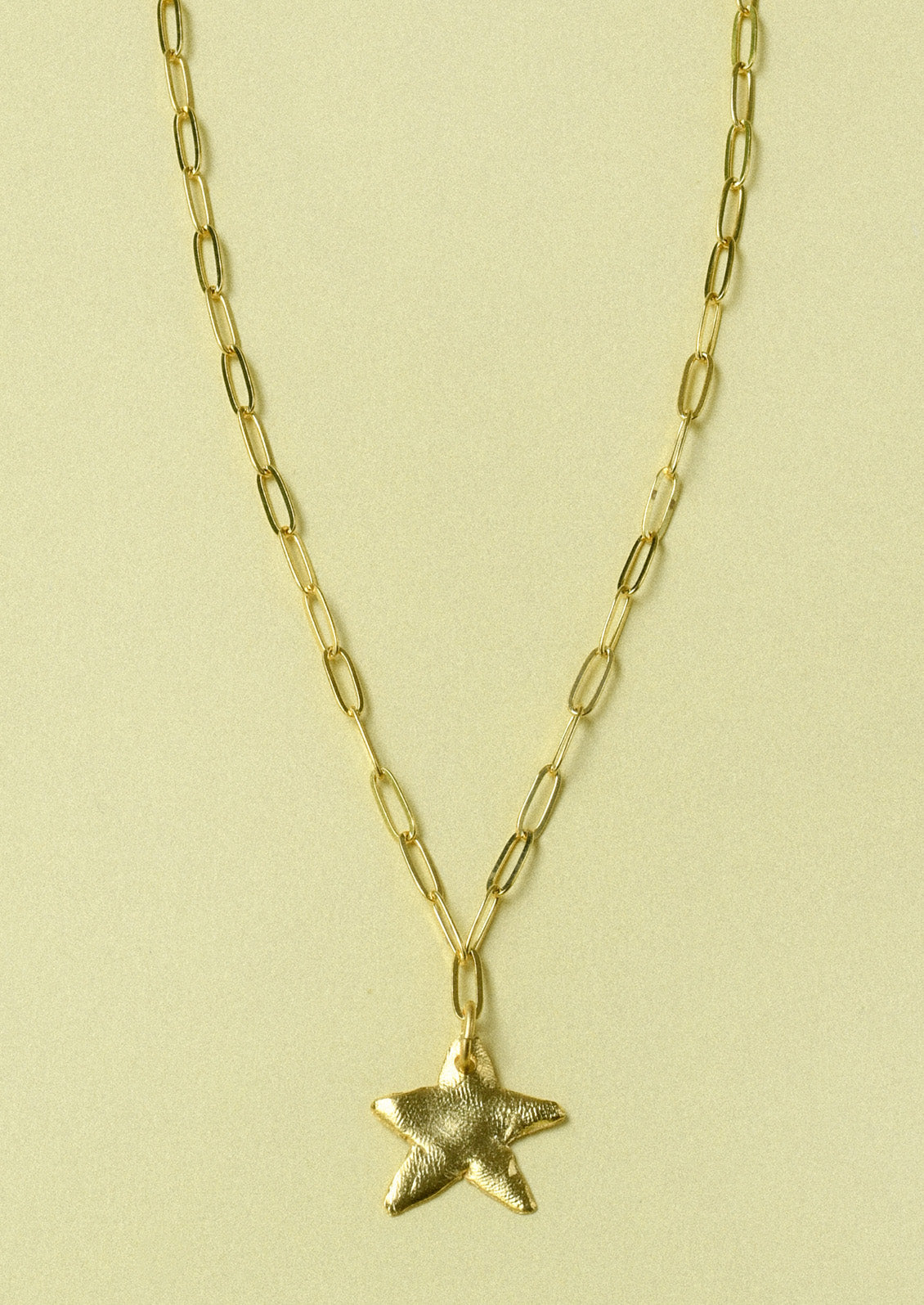 A gold paperclip chain necklace with a large star pendant.