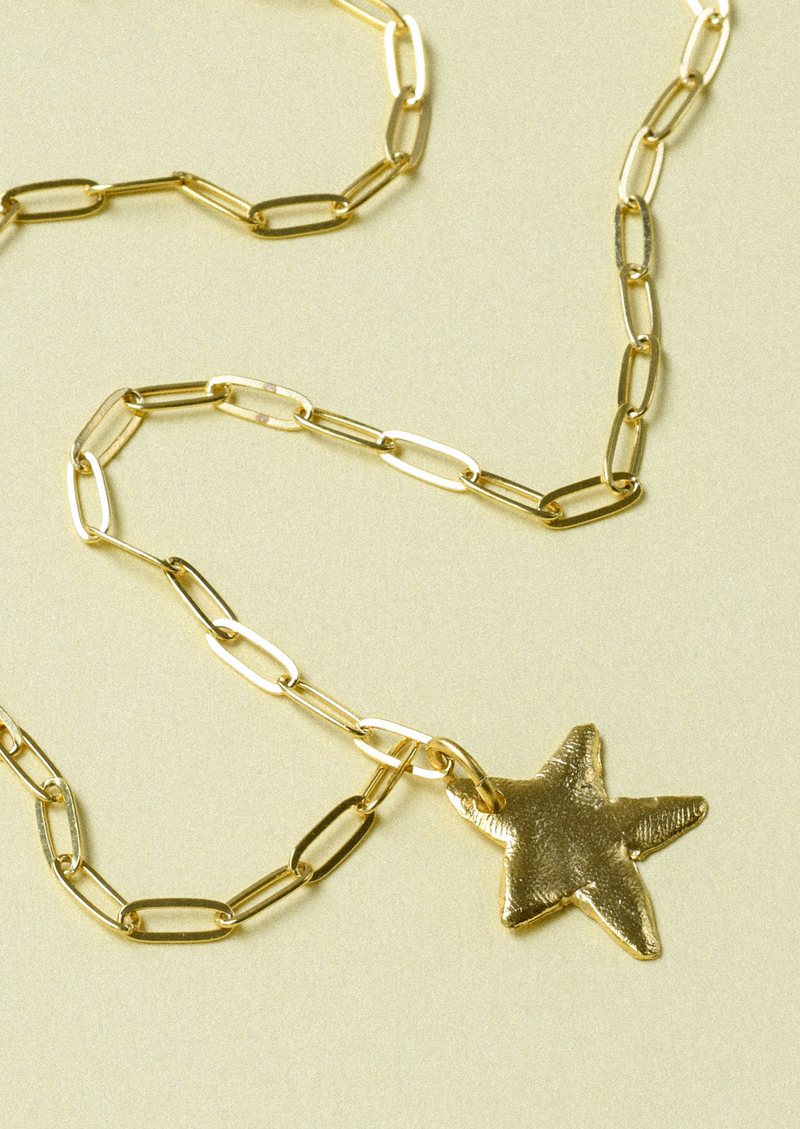 A gold paperclip chain necklace with a large star pendant.