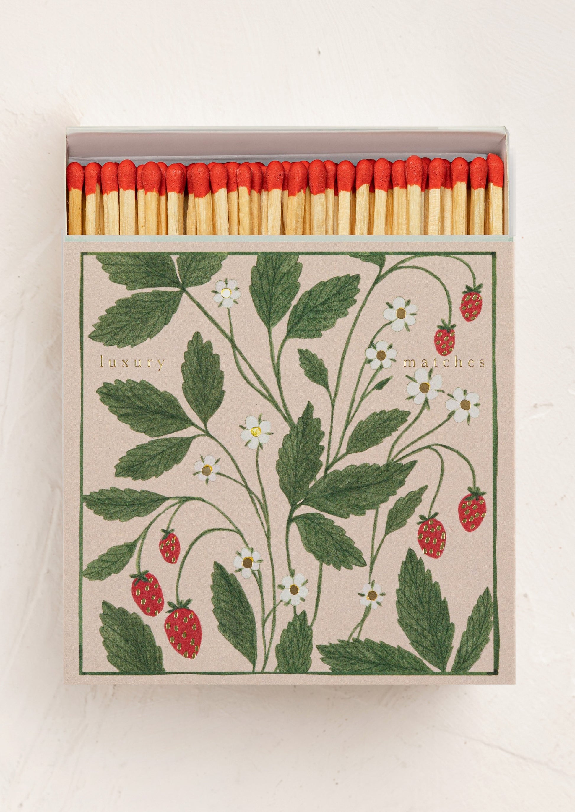 Matches with red tips in a box featuring strawberry and leaf design.