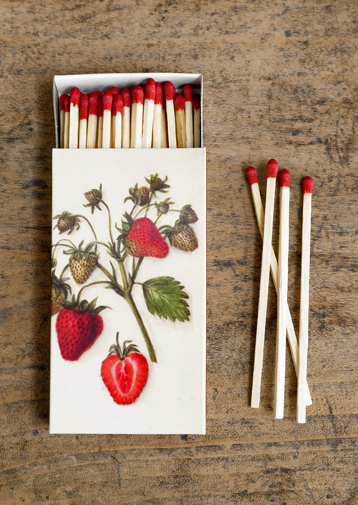 1: A box of long red tipped matches, box has vintage-inspired strawberry illustration.