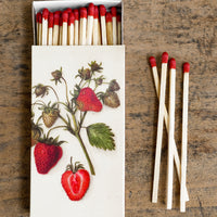 1: A box of long red tipped matches, box has vintage-inspired strawberry illustration.