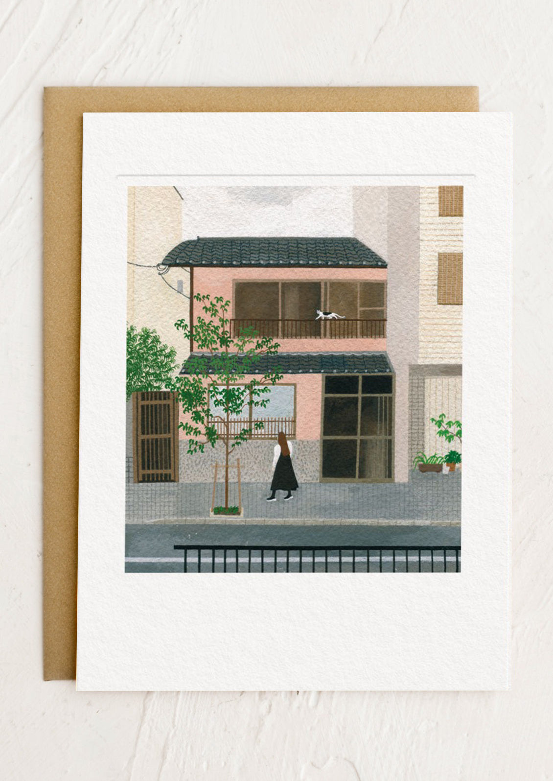 Framed artwork of a city street scene with a person walking past a building.