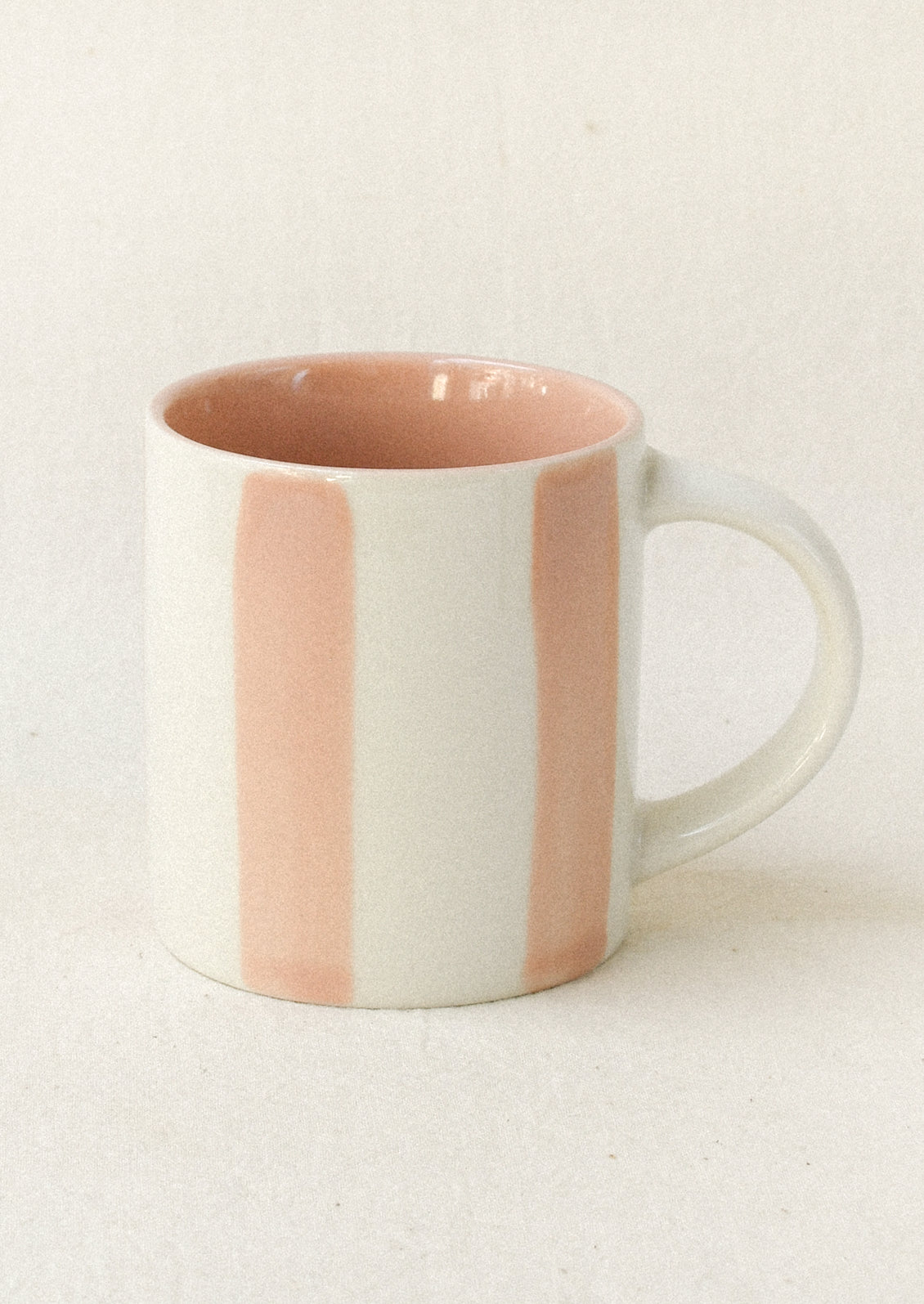 A small ceramic espresso cup with pink stripes.