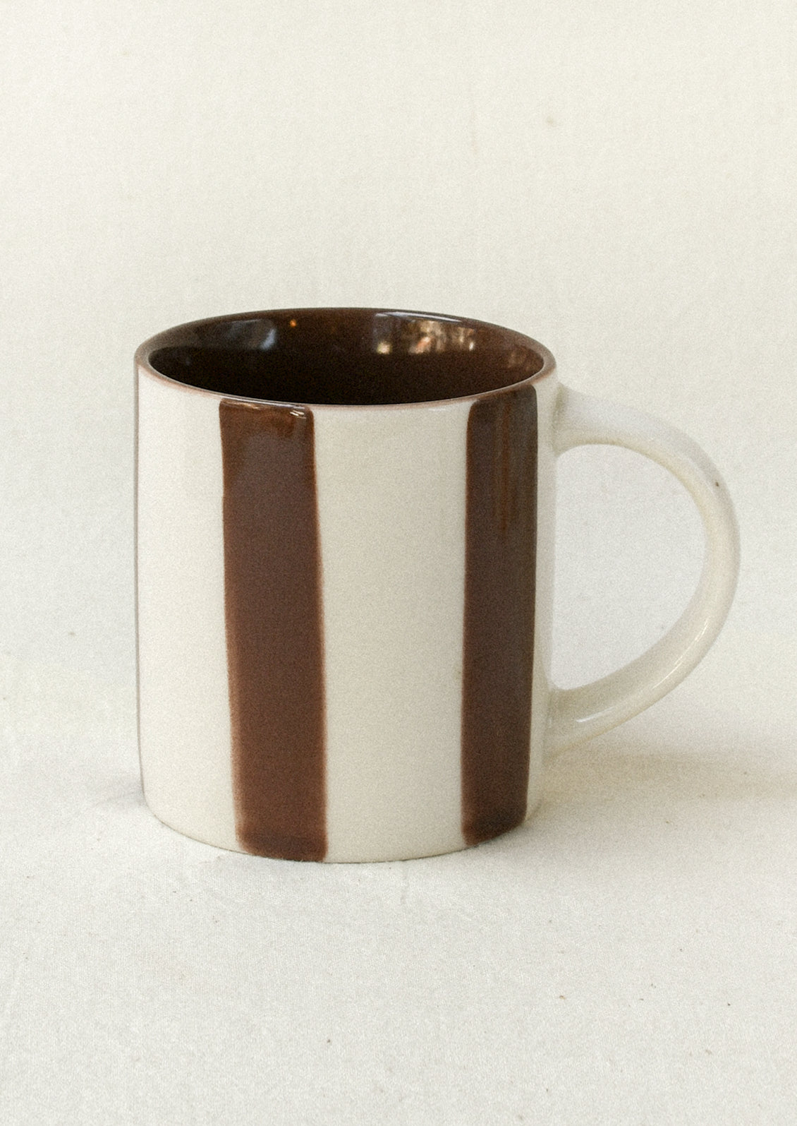 A small ceramic espresso cup with brown stripes.