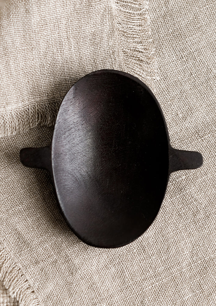 A carved wooden dish with oval shape and little side tabs.