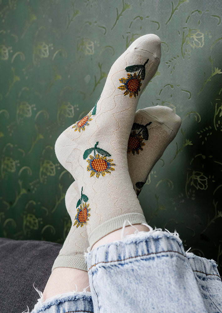 2: A pair of seafoam colored socks with sunflower pattern.