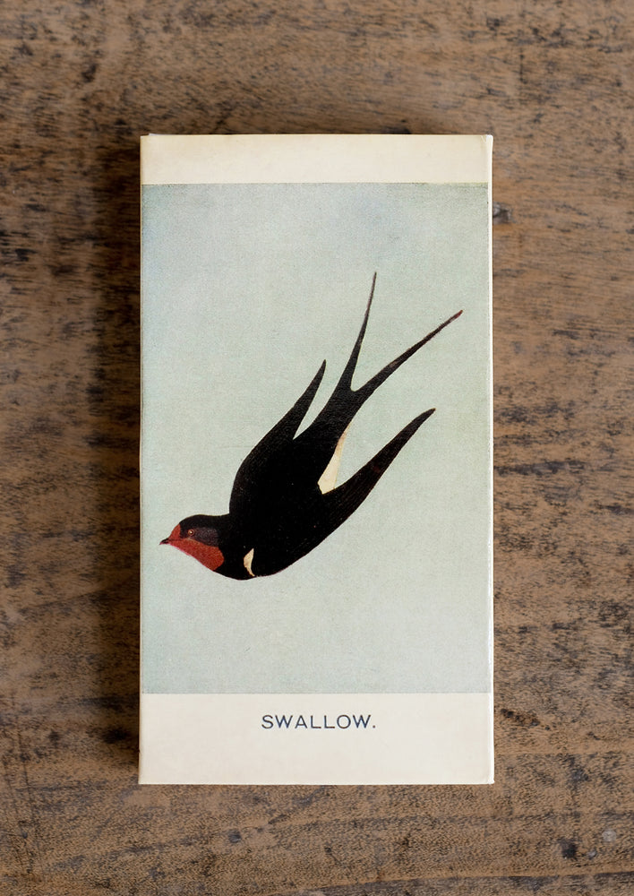 A swallow and magpie bird printed matchbox with red-tipped long matches.
