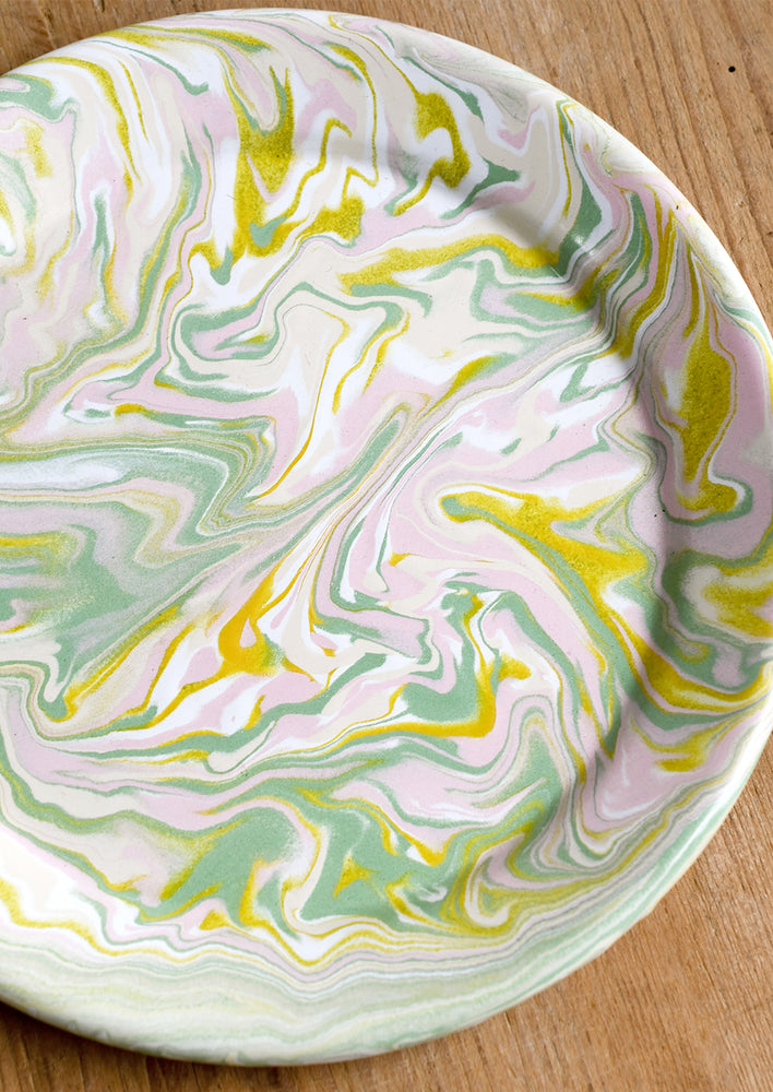 A round enamel plate with swirl pattern in pastel hues.
