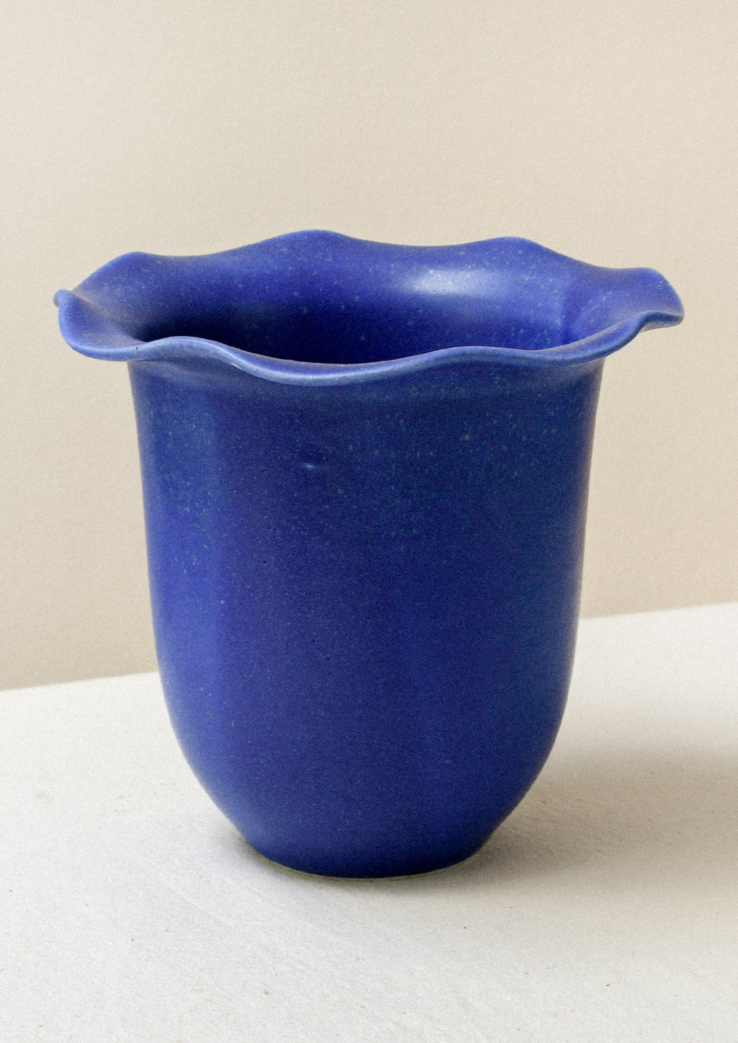 A cobalt blue ceramic speckled vase with a rippled lip design.