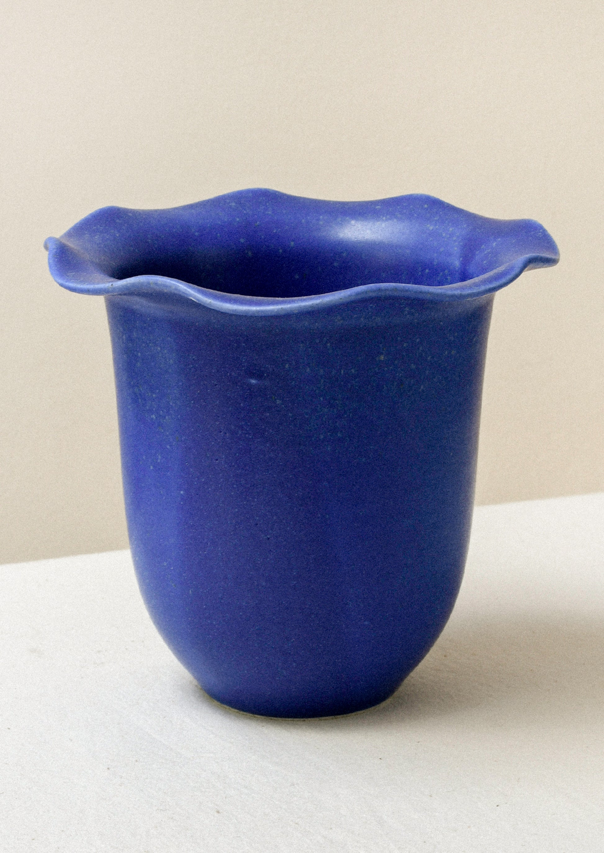 A cobalt blue ceramic speckled vase with a rippled lip design.