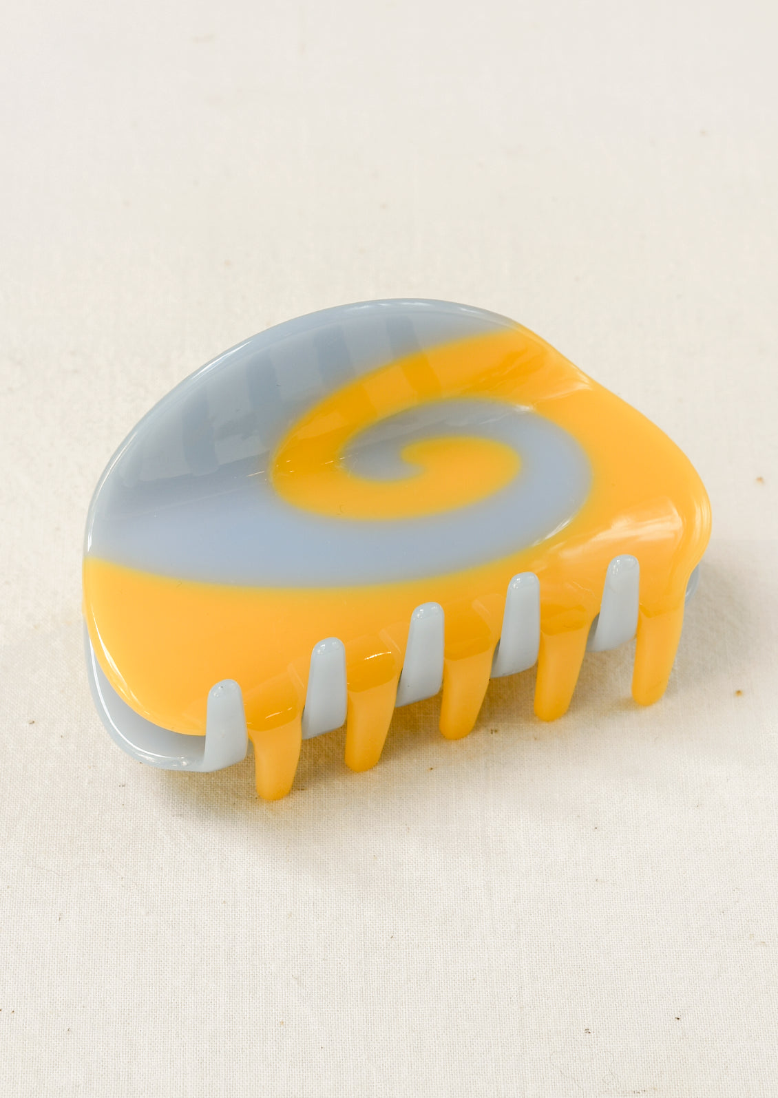 A hair claw clip with a light blue and yellow spiral design.