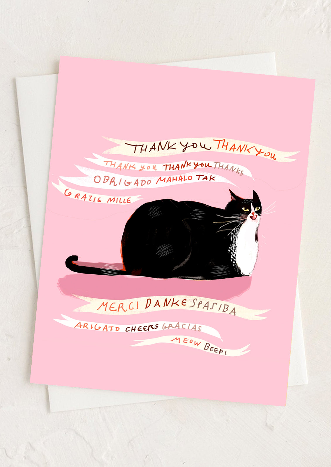 A pink greeting card with illustration of cat saying thank you in different languages.