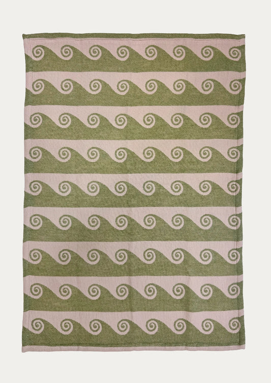 A jacquard weave tea towel with wave pattern in pink and green.