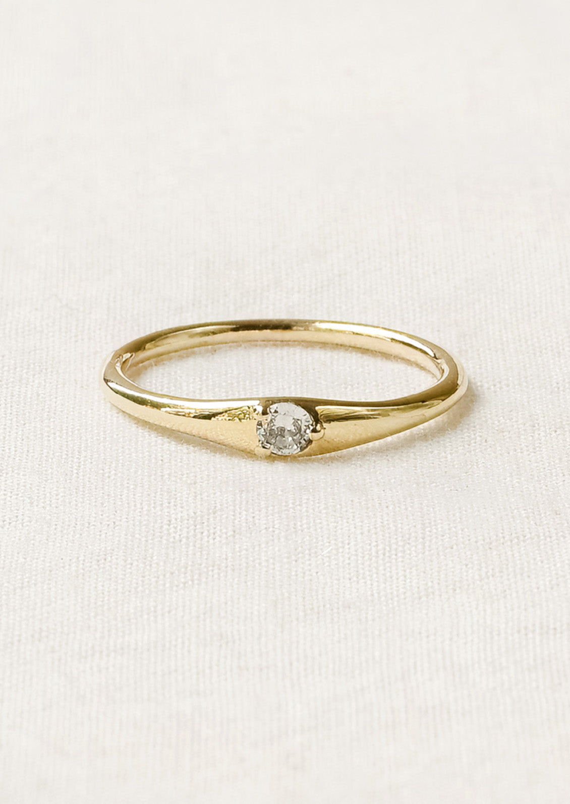 A simple gold ring with a solitaire cubic zirconia set in the center.
