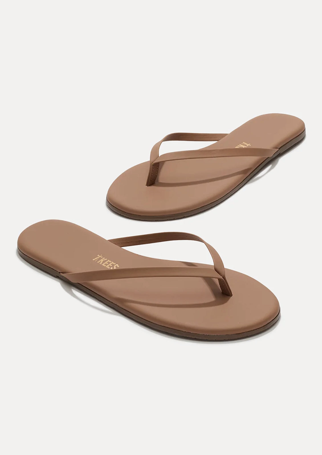 A pair of leather skinny strap TKEES sandals in nude.
