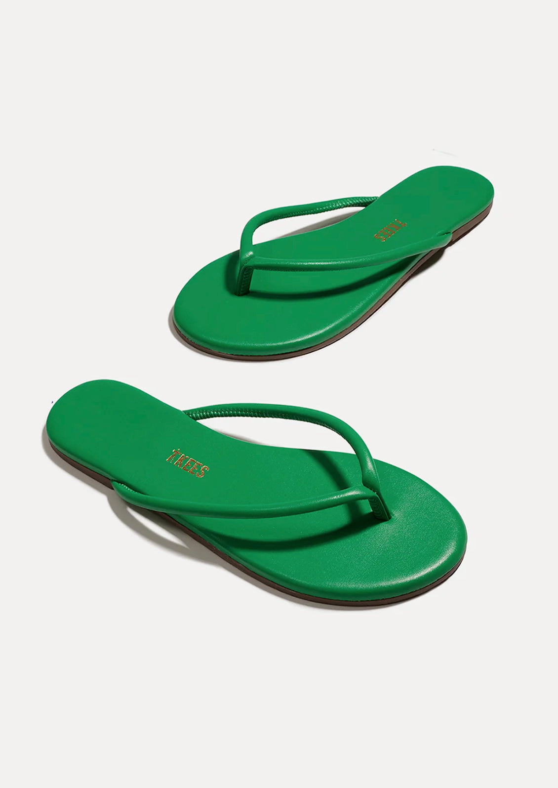 A pair of leather TKEES sandals with a tubular strap design in kelly green.