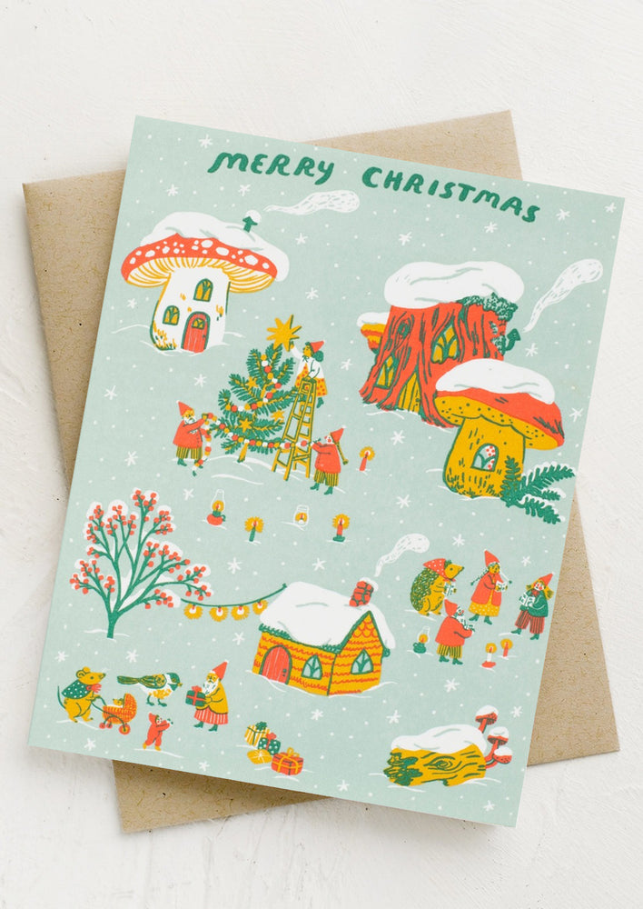 A whimsical village print card reading Merry Christmas.