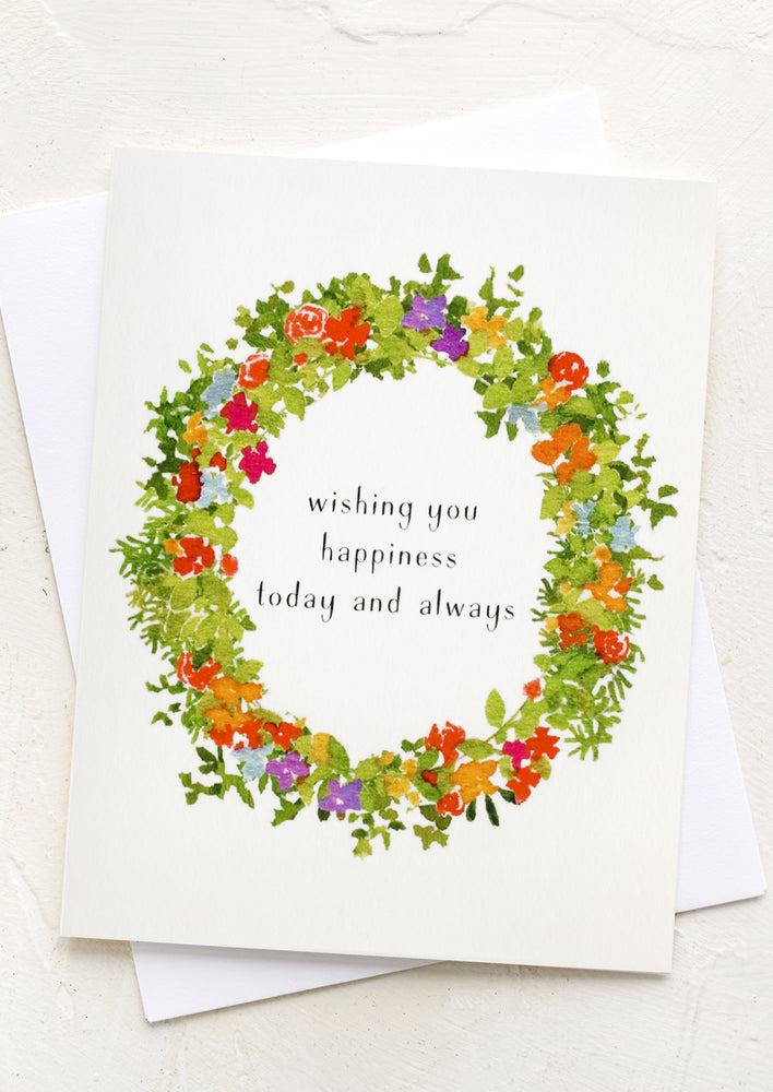 A floral wreath print card reading "wishing you happiness today and always".