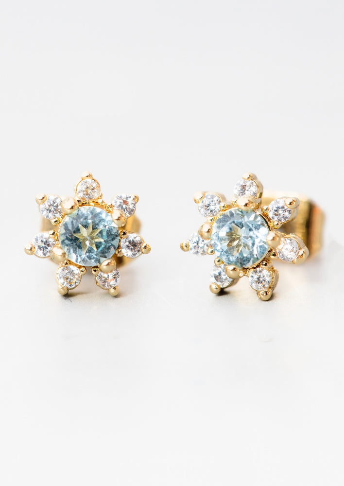 A pair of flower shaped studs with gemstone and crystal in blue.