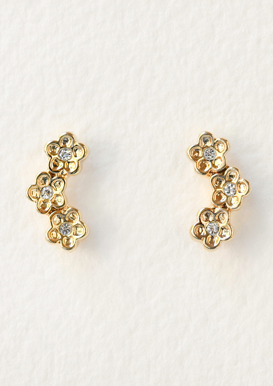 A pair of stud earrings each featuring a trio of flowers with crystals in the center.