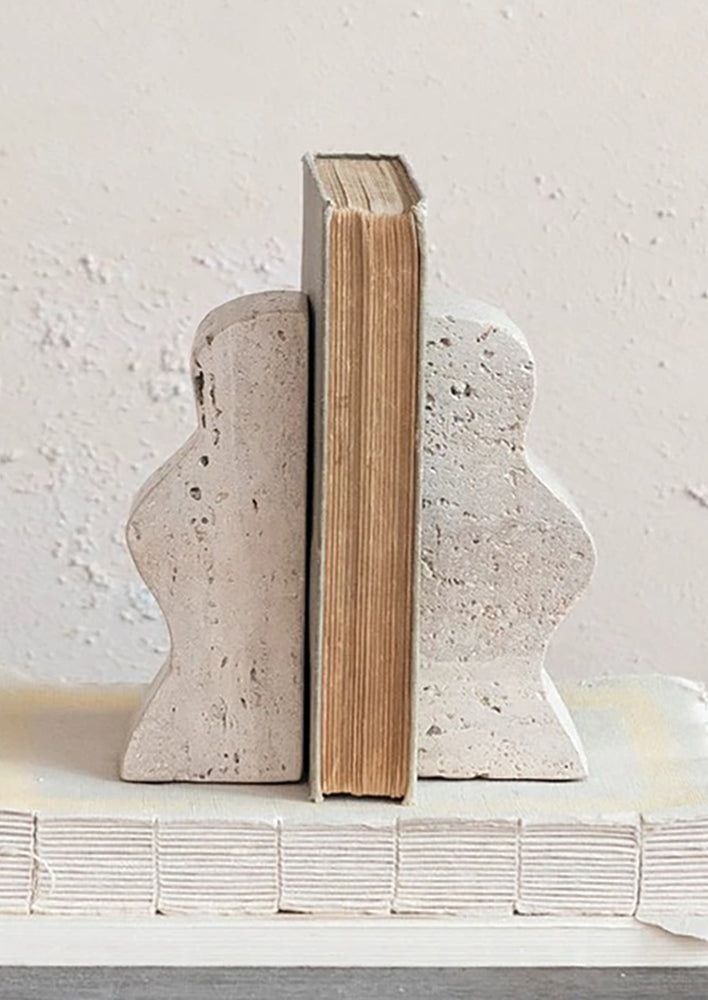 A pair of natural travertine bookends with wavy squiggle shape.