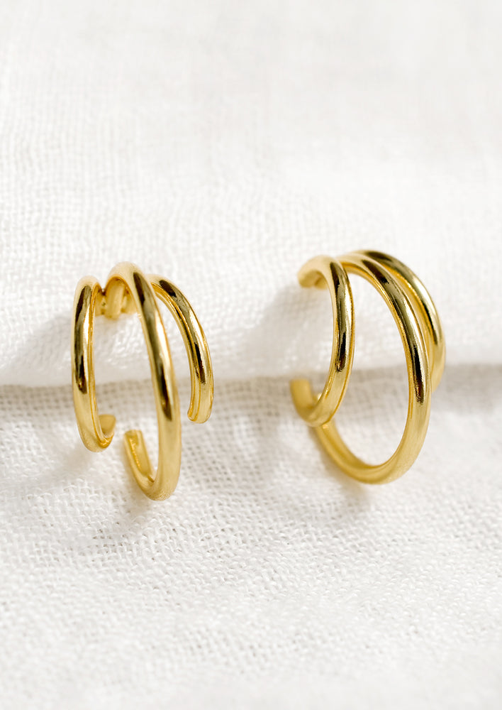 A pair of gold triple hoop earrings.